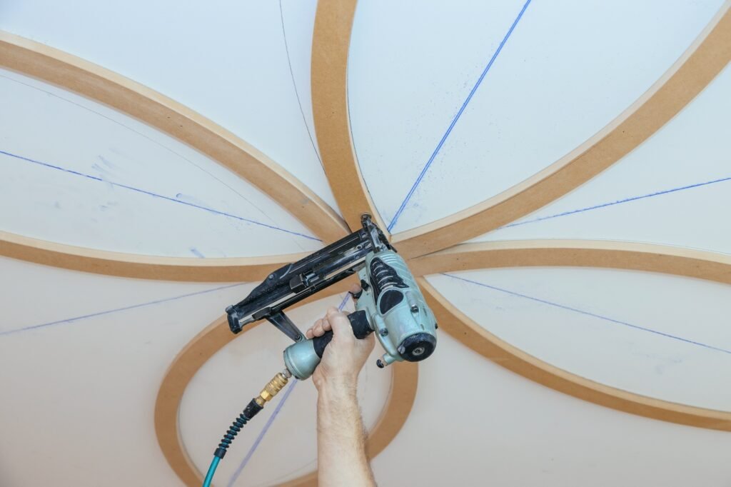 Installation of decorative mouldings on the ceiling carpenter using nail gun molding fragment