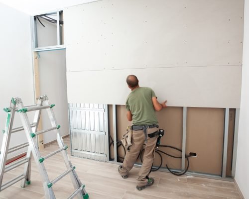 Worker building plasterboard wall.